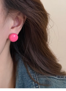 Gros plan d'une boucle d'oreille boule rose brillante portée par un mannequin