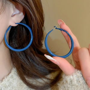 Detail of large Klein blue matte round hoop earrings shown on a model for a chic style