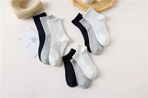 Flat lay of cotton crew socks in black, white, and grey colors on a light surface