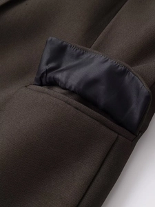 Detailed close-up of dark brown blazer fabric texture and professional pocket stitching