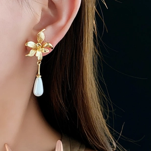 Close-up of 14K gold plated flower stud earrings with elegant teardrop pearl drops