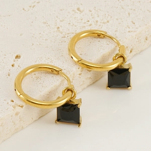 Golden titanium steel hoop earrings with black square zircon pendants on stone surface