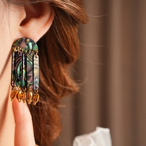 Close-up of bohemian tassel earrings with marble pattern acrylic and gold chain fringe