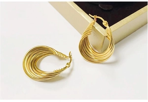 Detail of twisted spiral 18K gold earrings with polished texture on a jewelry box