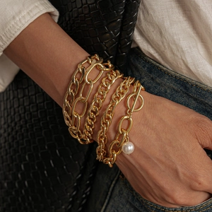 Detail of 5-piece gold chain bracelet set with pearl charm on model wrist