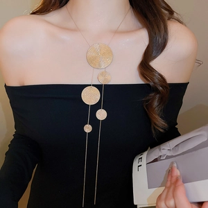 Gros plan d'un collier en Y doré à plusieurs couches avec des pendentifs circulaires