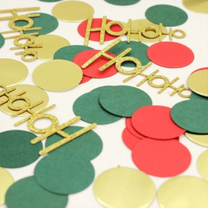 Close-up of red, green, and gold Christmas confetti with glittery HoHoHo letter cutouts