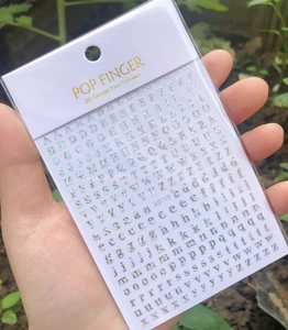 Detailed close-up of 3D silver laser alphabet nail stickers with holographic finish