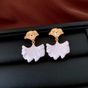 Macro shot of ginkgo leaf earrings with drop-shaped zircon on a black jewelry box