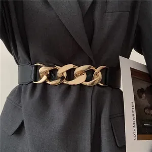 Close-up of a wide black leather waist belt with chunky gold chain buckle on grey blazer