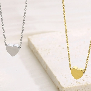 Minimalistische Herz-Halskette in Gold und Silber auf natürlichem Stein-Hintergrund