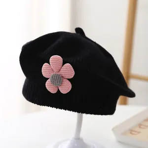 Detail of black knitted baby beret featuring a 3D pink corduroy flower decoration