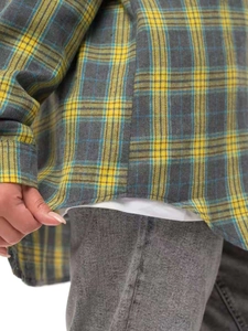 Detailed view of grey and yellow plaid flannel shirt hem styled with grey denim jeans