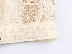 Close-up of beige mesh fabric with golden sequins and 3D cord embroidery detail