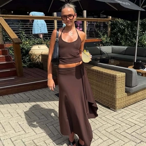Deep brown two-piece set featuring a halter crop top and irregular cut long maxi skirt