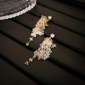 Détail de boucles d'oreilles à pompons longs avec cristaux brillants et chaînes dorées