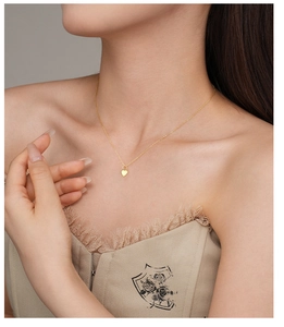 Close-up of a gold S925 silver heart pendant necklace on a female model's neck