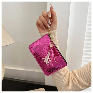 Close-up of pink crocodile texture purse with golden zipper and a white tassel