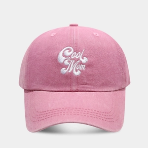Close-up of pink washed cotton baseball cap featuring white Cool Mom script embroidery