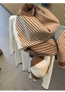 Detail of soft cashmere-like scarf with brown and beige striped pattern and blue accents