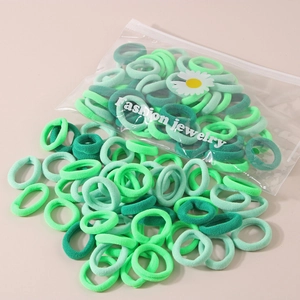 Sortierte grüne elastische Haargummis in einem transparenten Beutel mit Gänseblümchen.