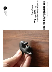 Detail of matte black cat drawer handle with hand-polished finish on wood