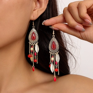 Boucles d'oreilles bohèmes avec perles rouges et feuilles dorées portées par un mannequin