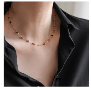 Close-up of minimalist gold beaded necklace with colorful natural stones on a model