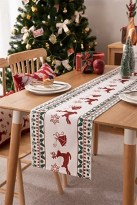 Christmas table runner with red reindeer and green holly patterns on a wooden table