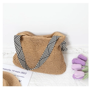 Detail of hand-woven straw tote bag with striped shoulder strap and beige inner lining