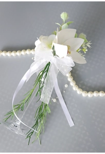 Detail of white artificial orchid with green leaves and ribbon for wedding glass decor