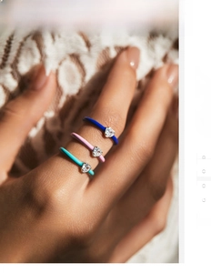 Close-up of three colorful enamel heart rings with sparkling zircons on white lace