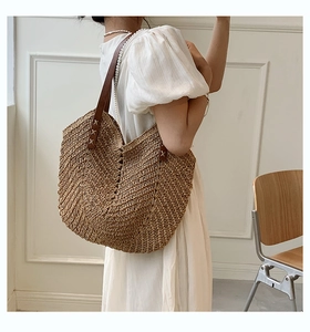 Detail of hand-woven straw tote bag with brown leather straps for summer beach vacation