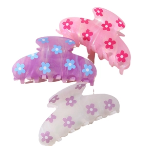 Three acetate hair claws with floral patterns in pink, purple and white on white background