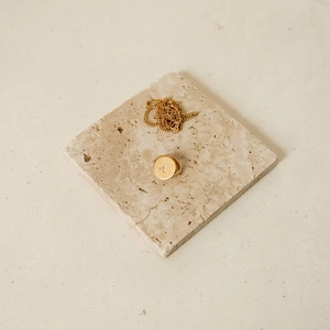 Detail of gold oval pendant necklace and initial A signet ring on stone display stand