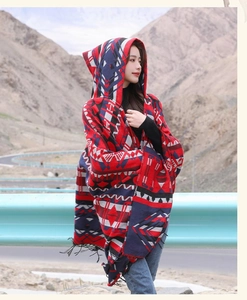Photo en extérieur d'un poncho ethnique à capuche avec motifs rouges et détails de franges