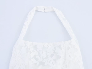 Detailed view of white floral lace neckline and halter strap with button fastening