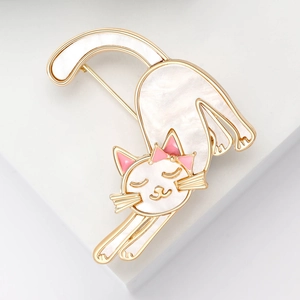 Detailed view of a golden enamel cat brooch with white mother of pearl inlay and pink bow