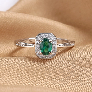Elegant silver ring with oval emerald-green gemstone and halo diamond settings