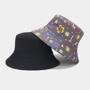 Detail of reversible bucket hats in solid black and purple cartoon mushroom print