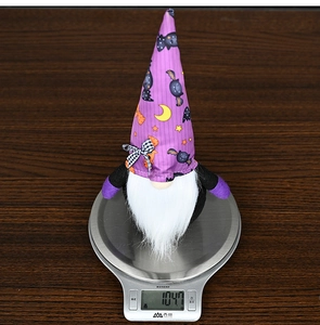 Close-up of Halloween purple gnome plush decoration showing 104.7g weight on a scale