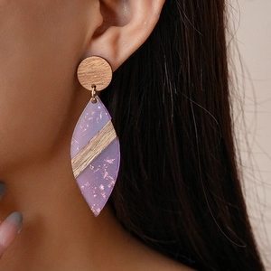Detailed view of bohemian wood and purple resin leaf earrings worn by a model