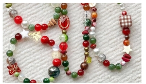Close-up of Christmas phone charm with colorful beads, stars, and festive tree shapes