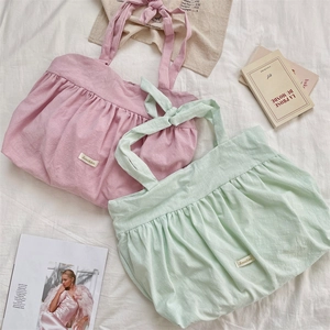 Close-up of pleated canvas tote bags in soft pink and green with ribbon bow straps