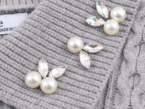 Primer plano de jersey de punto gris con perlas blancas y cristales decorativos