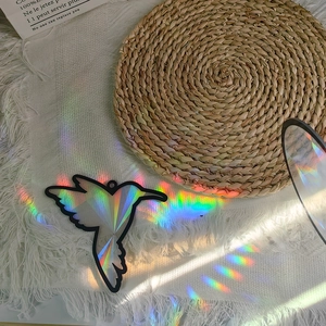 Macro shot of hummingbird suncatcher showing prismatic rainbow reflections on white rug