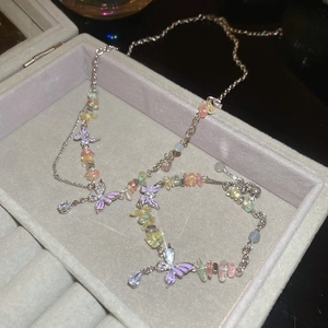 Detail of silver chain necklace with purple butterfly pendant and colorful gemstones