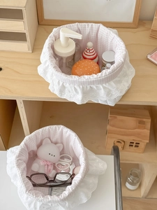 Close-up of pink checkered storage basket with white lace ruffle and bow embroidery