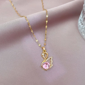 Close-up of golden swan pendant with pink gemstone and white zircon on a water wave chain