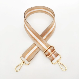 Detail of adjustable nylon bag strap with gold and white stripes and metal buckles